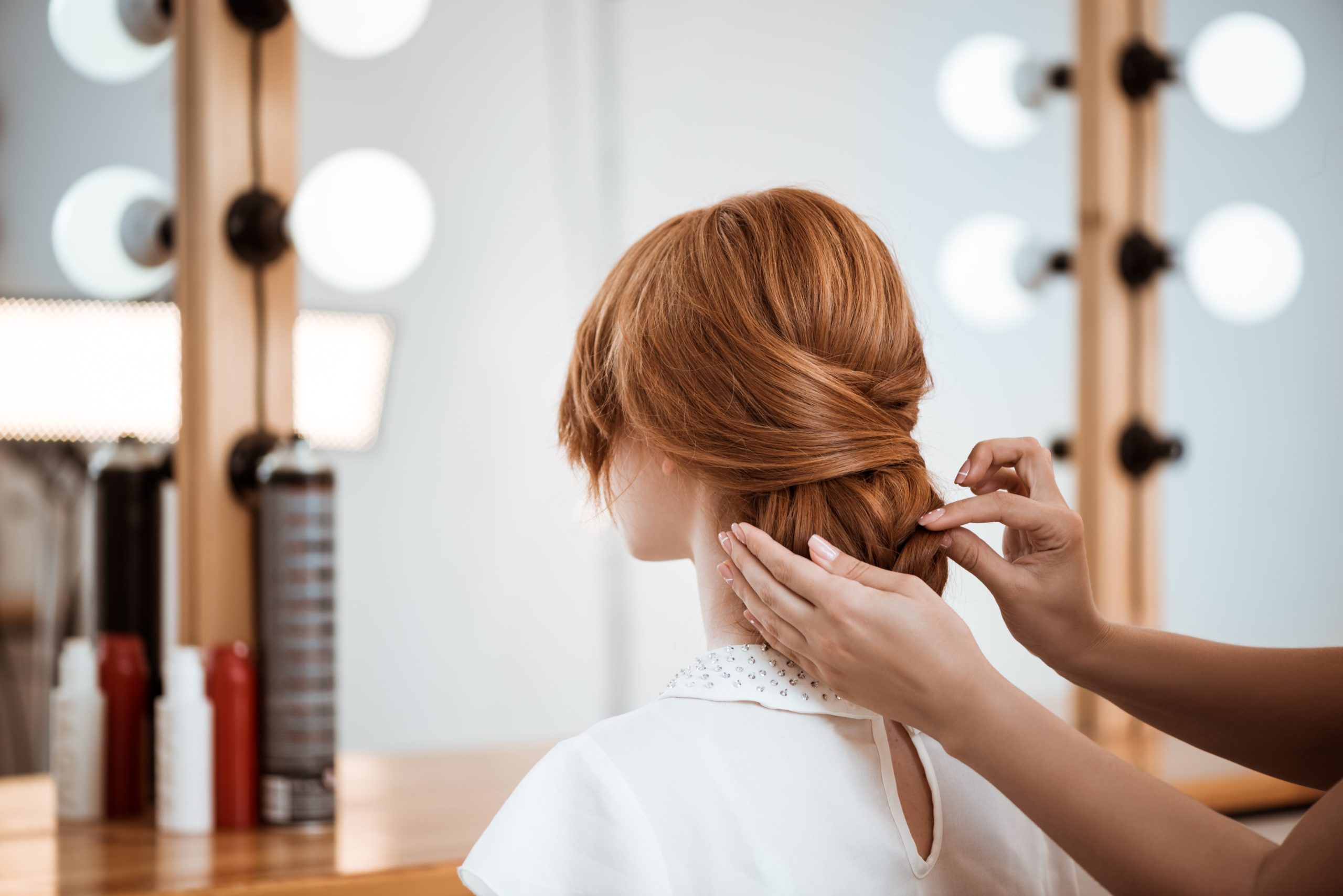 Female hairdresser making a hairstyle for a redhead woman